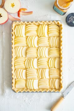 an apple tart with sliced apples on the side next to a knife and butter