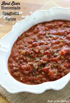 homemade spaghetti sauce in a white bowl on a wooden table with a spoon and napkin