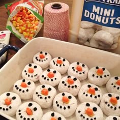 a pan filled with frosted snowman cookies next to a spool of candy