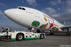 an airplane with hello kitty painted on the side is being towed by a flatbed truck