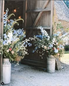 two buckets filled with flowers sitting in front of a barn