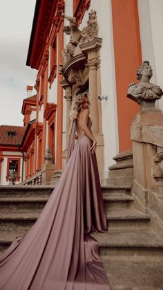 a woman in a long dress standing on some steps