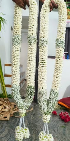 white flowers are tied to the side of a pole in front of a man's hand