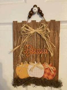 a wooden sign that says blessing hanging on a door with two pumpkins in front of it