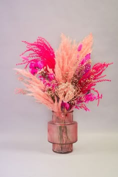 a pink vase filled with lots of different colored flowers on top of a white table