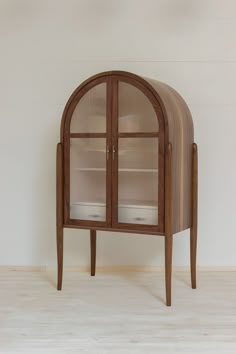 an arched wooden cabinet with glass doors