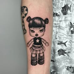 a small tattoo on the arm of a girl with an adorable doll in her hand