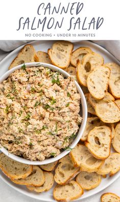 a white plate topped with bread slices and a bowl of salmon salad