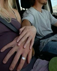 a man and woman sitting in the back seat of a car with their hands wrapped around each other