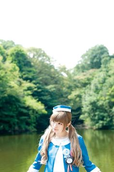 a girl in blue and white outfit standing on the edge of a body of water