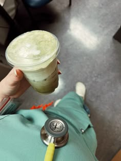 a person with a stethoscope on their arm holding up a cup of drink