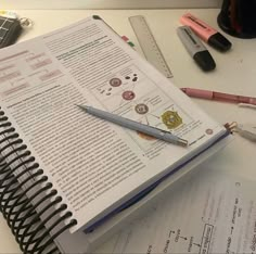 an open book sitting on top of a desk next to a pen and calculator