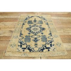 an antique persian rug with blue and beige colors on wooden flooring, in the middle of