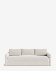 a white couch sitting on top of a wooden floor next to a wall with a light colored