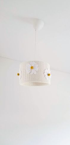 a white ceiling light with flowers hanging from it's centerpiece in a room