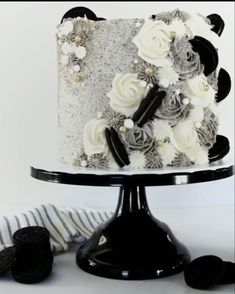 a black and white cake with flowers on it sitting on a table next to cookies