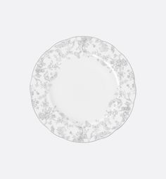 an empty white plate with floral designs on the rim and bottom, against a gray background