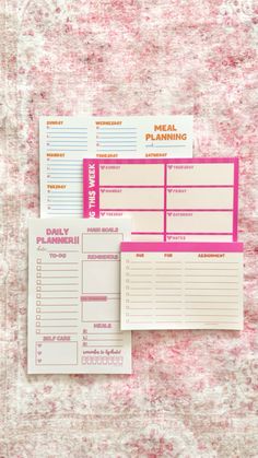 two pink and white planner pages sitting on top of a table