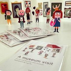 several paper dolls are on display in an art gallery with posters and paintings behind them