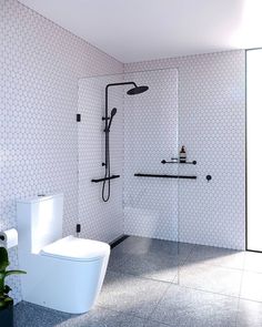 a white toilet sitting next to a shower in a bathroom with tiled walls and floor