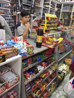 two people standing in front of a store filled with food and confection items