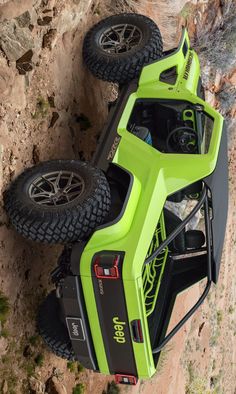 the rear end of a green car with two large tires