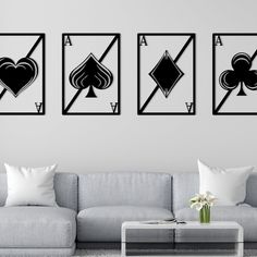 three black and white playing cards are hanging on the wall above a couch in a modern living room