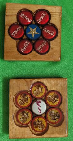 two wooden coasters with coca - cola buttons on them sitting on a green surface