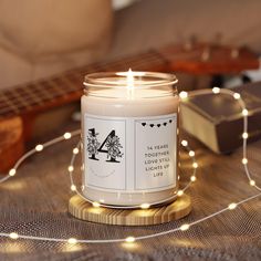 a white candle sitting on top of a wooden table next to a string of lights