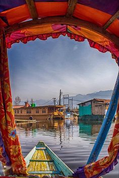 there is a boat in the water with colorful curtains on it's windowsill