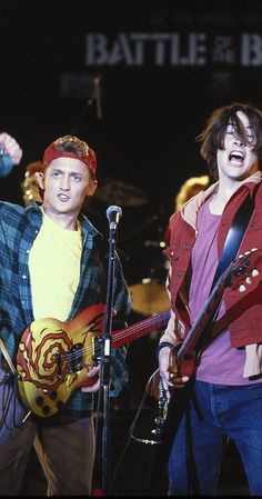 two young men singing into microphones while holding guitars