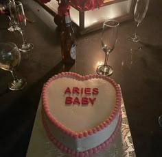 there is a cake with the words aries baby on it next to wine glasses