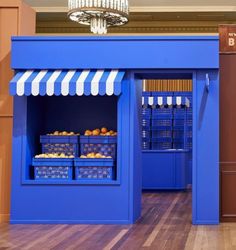 a store with blue walls and white awnings on the front, filled with fruit