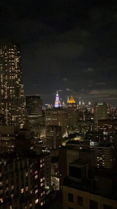 the city skyline is lit up at night, with skyscrapers in the foreground