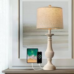 an iphone is plugged into the charging station on a table next to a lamp