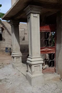 an old stone building with two pillars and a cage on the outside, in front of it