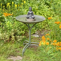 a small buddha statue sitting on top of a table in the middle of some flowers