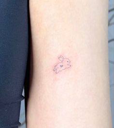 a small tattoo on the back of a woman's left arm with a teddy bear