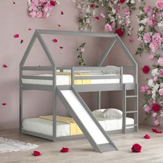 a bunk bed with a slide in front of it and flowers on the wall behind it