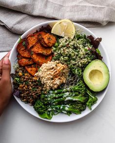 a white plate topped with lots of food next to an avocado and lemon wedge