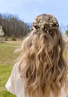 the back of a woman's head with long hair and flowers in her hair