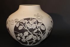 a black and white vase sitting on top of a table next to a dark background