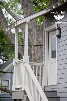 a white porch with stairs leading up to the front door and second story window on a gray house