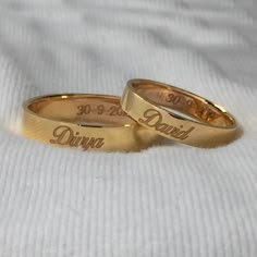 two gold wedding rings with the names of their bride and groom