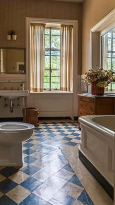 a bathroom with blue and white checkered flooring next to a bathtub in the corner