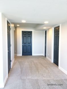 an empty room with black doors and white walls