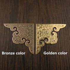 two brass tone metal wall hangings on a wooden surface with the words bronze color and golden color