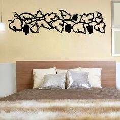 a bedroom with a bed and wall decal that has vines on the headboard