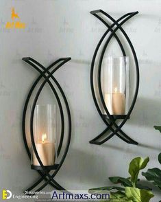 two wall sconces with candles in them are hanging on the wall next to a potted plant