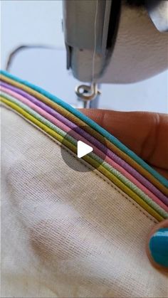 someone is using a sewing machine to sew on the fabric with colored strips in front of them